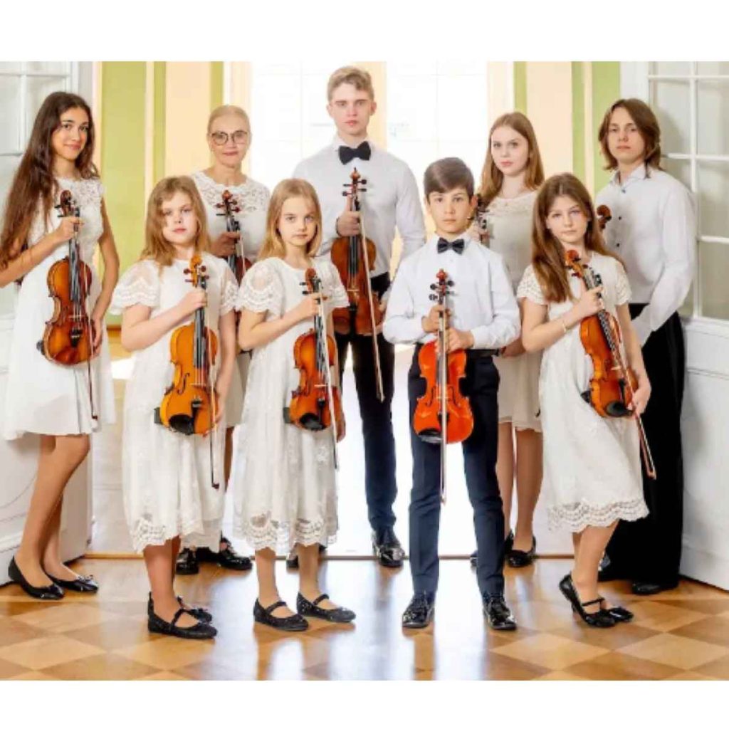 9 musicians dressed in white holding violins 